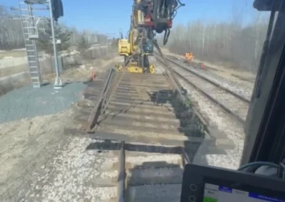 Interior view of a train car showing a crane working on the tracks outside the window.